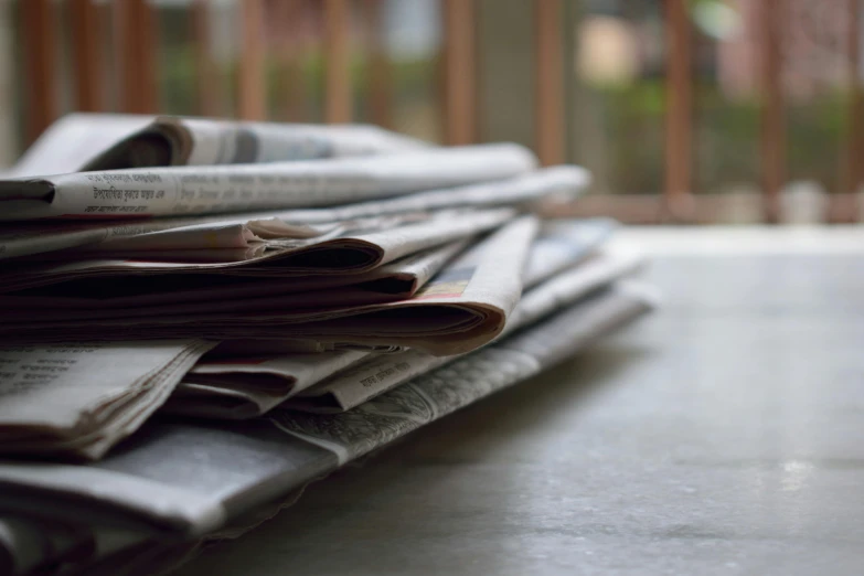 a pile of newspapers sitting on top of a table, by Carey Morris, unsplash, private press, 15081959 21121991 01012000 4k, instagram post, family friendly, middle close up