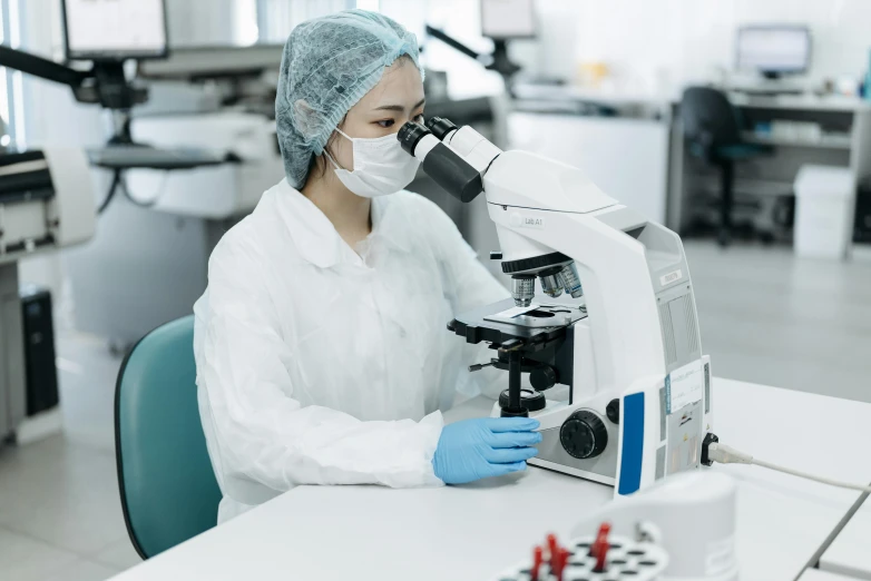 a woman in a lab coat looking through a microscope, surgical gown and scrubs on, jinyiwei, thumbnail, no cropping