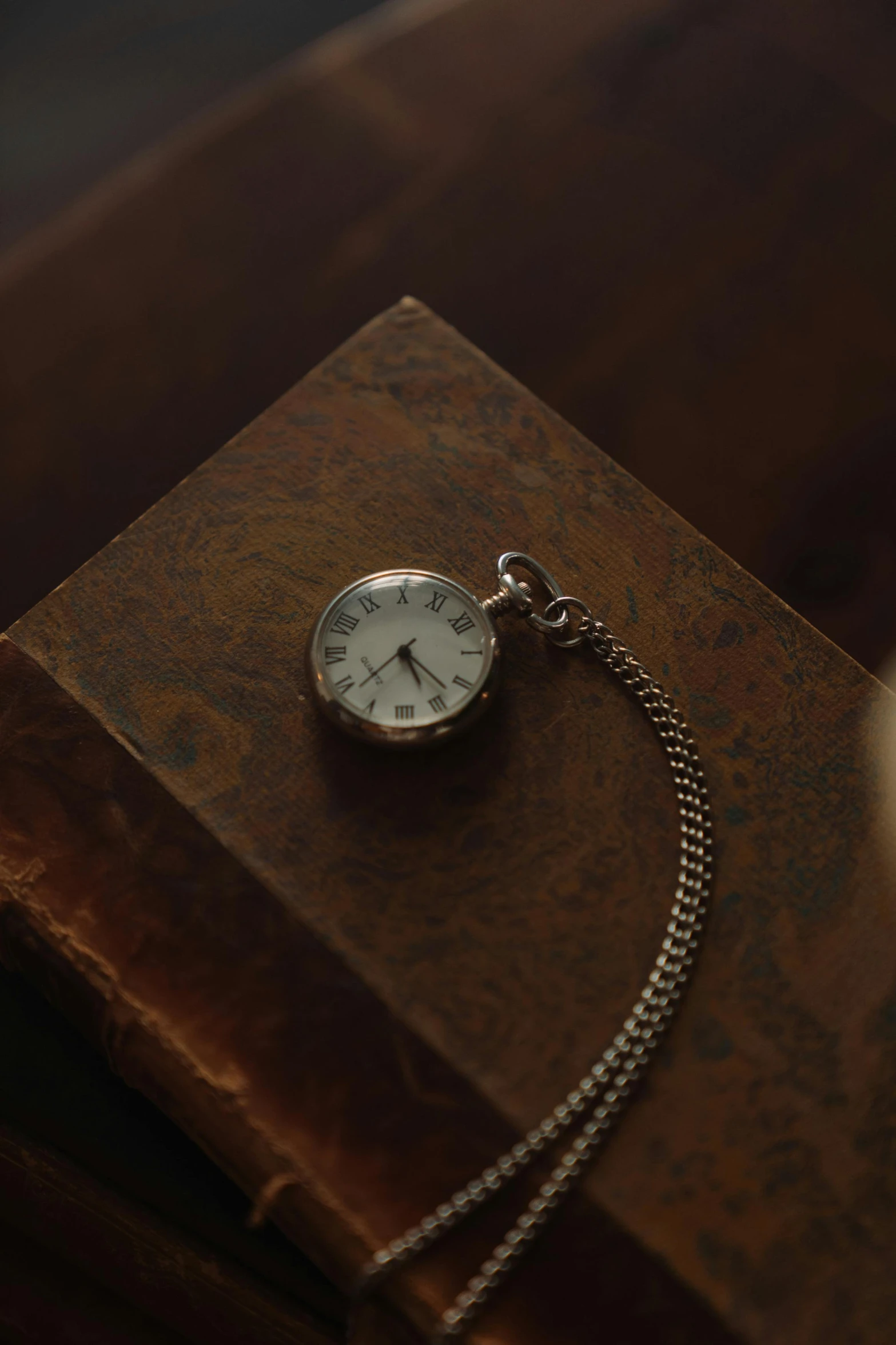 a pocket watch sitting on top of a book, an album cover, by Elsa Bleda, unsplash, photorealism, necklace, ignant, silver，ivory, realistic footage