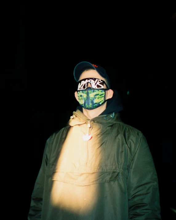 a man wearing a face mask in the dark, an album cover, inspired by Elsa Bleda, graffiti, green visor, low quality photo, (((low light))), lsd face