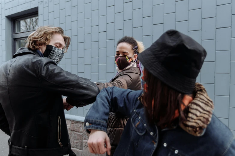 a group of people standing next to each other on a sidewalk, by Emma Andijewska, trending on pexels, graffiti, hands shielding face, black bandana mask, fist fight, woman holding another woman