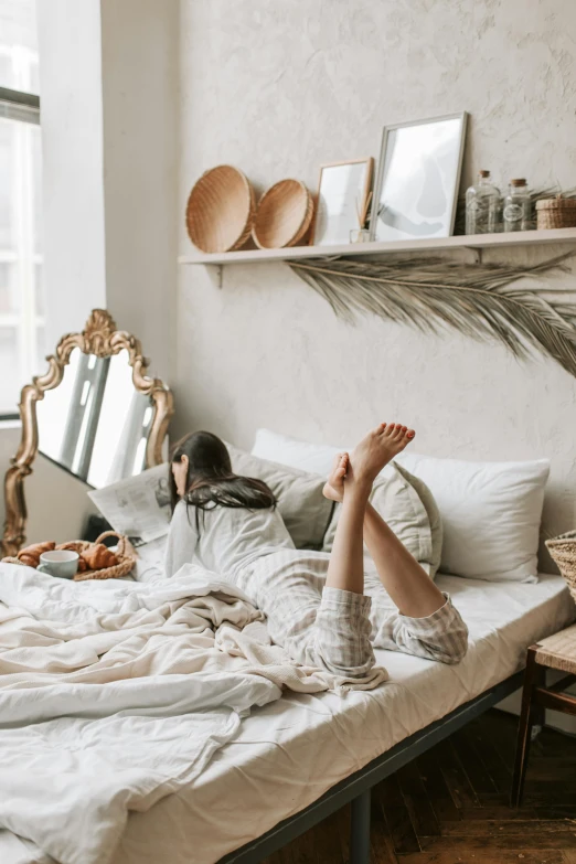 a person laying on a bed in a room, pexels contest winner, boho neutral colors, inside a cozy apartment, profile image, furnished room