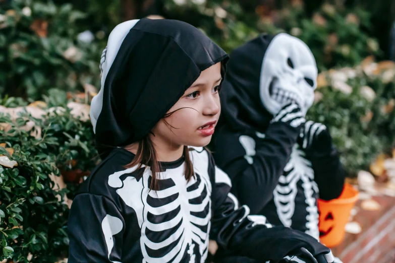 two children in skeleton costumes sitting on a bench, by Emma Andijewska, pexels, black haired girl wearing hoodie, costume desig, exposed bones, uploaded