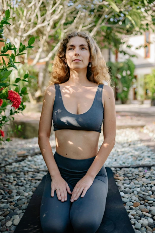 a woman is sitting on a yoga mat, a portrait, by Carey Morris, wearing a cropped top, bali, f / 2 0, slate