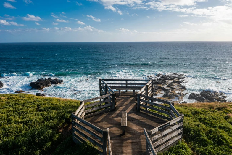 a wooden bench sitting on top of a lush green hillside next to the ocean, wooden platforms, rock pools, 400 steps, reefs