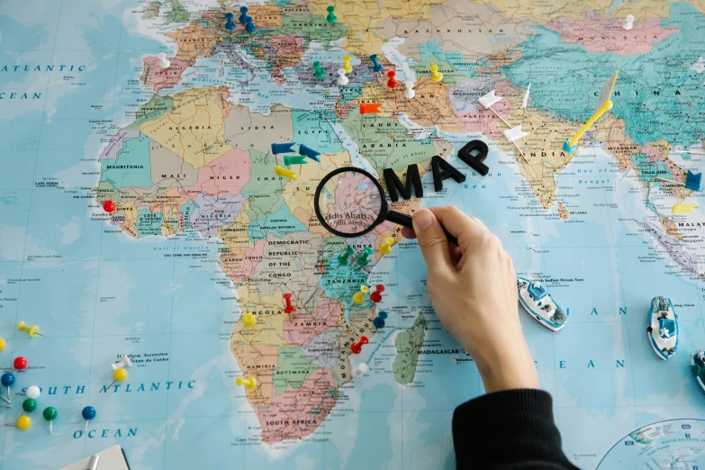 a person holding a magnifying glass over a map, an album cover, by Julia Pishtar, pexels contest winner, middle east, board games, where is waldo, 1 6 x 1 6