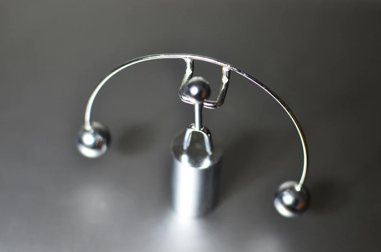 a close up of a metal object on a table, inspired by Oskar Schlemmer, unsplash, chrome facial piercings, fully frontal view, libra, landing gear