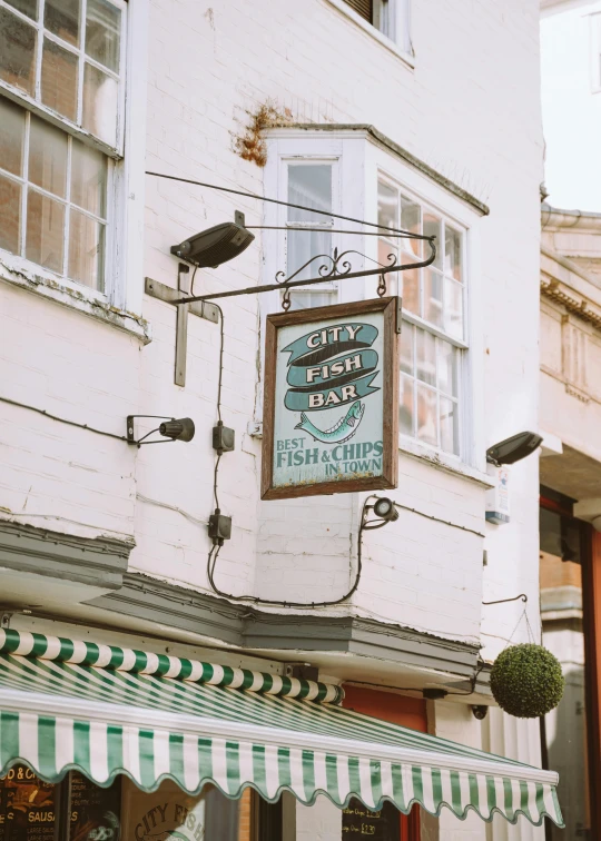 a white building with a green and white awning, poster art, by Paul Bird, unsplash, renaissance, pub sign, crap fish, 2 5 6 x 2 5 6 pixels, ivy's