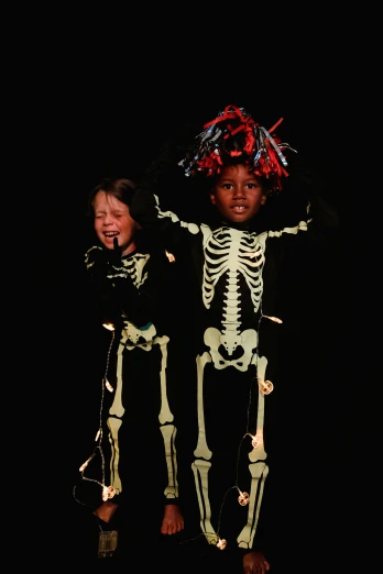 a couple of kids standing next to each other, by Ellen Gallagher, vanitas, glowing bones, slide show, diverse costumes, taken in the late 2010s