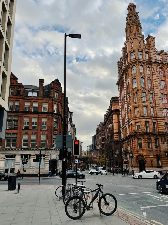 a couple of bikes parked on the side of a street, inspired by Thomas Struth, pexels contest winner, manchester, gorgeous buildings, background image, lampposts