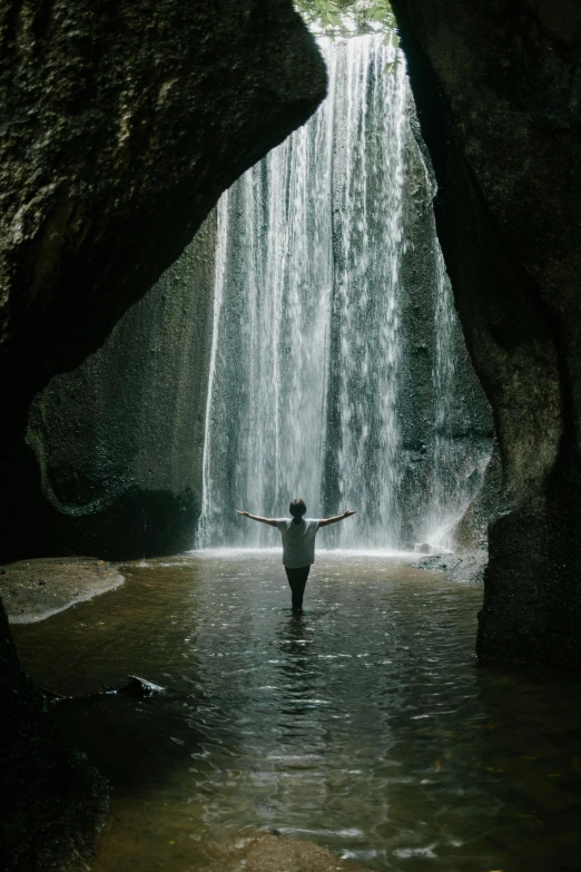 a person standing in front of a waterfall, caves, bali, but minimalist, stretch