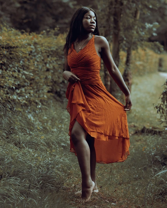 a woman in an orange dress walking in the woods, pexels contest winner, renaissance, sexy black woman walks past them, ( ( dark skin ) ), pose 4 of 1 6, desaturated