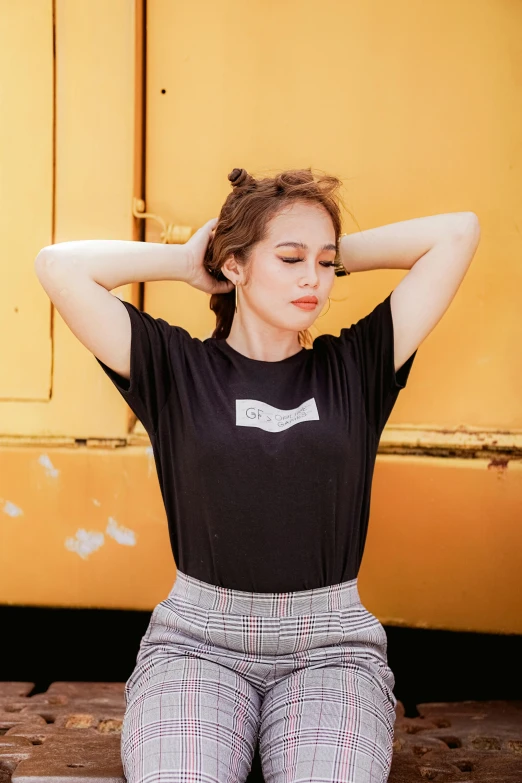 a woman sitting on the ground with her hands behind her head, a picture, inspired by Ruth Jên, trending on pexels, black t - shirt, kat dennings, streetwear, asian women