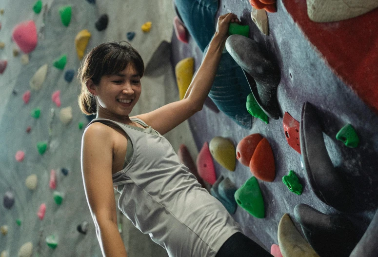 a woman standing in front of a climbing wall, a portrait, pexels contest winner, chun li at the gym, manuka, 🦩🪐🐞👩🏻🦳, happy girl