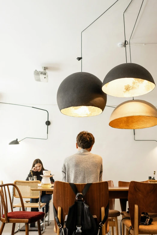 a couple of people that are sitting at a table, by Jan Tengnagel, trending on unsplash, light and space, light fixtures, scandinavian design, cafe