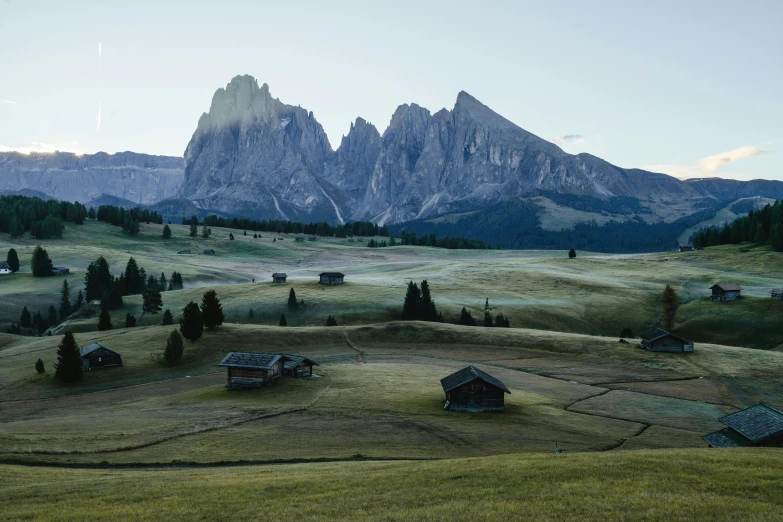 a group of houses sitting on top of a lush green hillside, a detailed matte painting, unsplash contest winner, dolomites in background, late summer evening, grain”, hasselblad photo