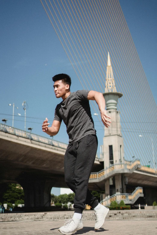 a man running across a bridge with a clock tower in the background, inspired by Cheng Jiasui, pexels contest winner, happening, wearing a track suit, square, malaysian, 8k octan advertising photo