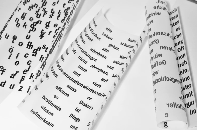 a roll of paper sitting on top of a table, a photocopy, by Kristian Zahrtmann, unsplash, letterism, set against a white background, various sizes, alien language, german