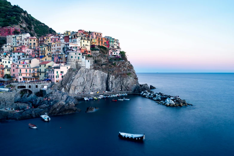 a group of boats floating on top of a body of water, by Patrick Pietropoli, pexels contest winner, renaissance, cliff side at dusk, colorful houses, slide show, conde nast traveler photo