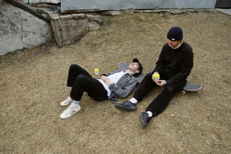 a man sitting on the ground next to another man on a skateboard, milkboys, asleep, julia hetta, warm spring