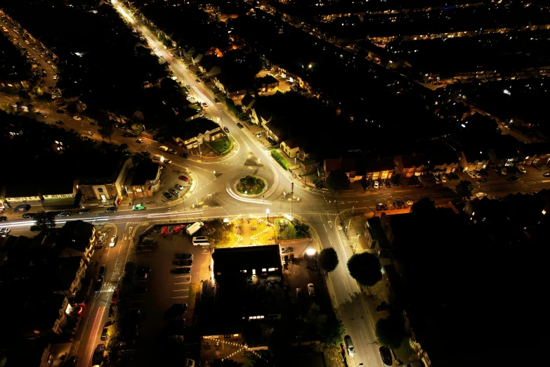 an aerial view of a city at night, by Dave Allsop, happening, street lighting, square, high quality picture, low detailed