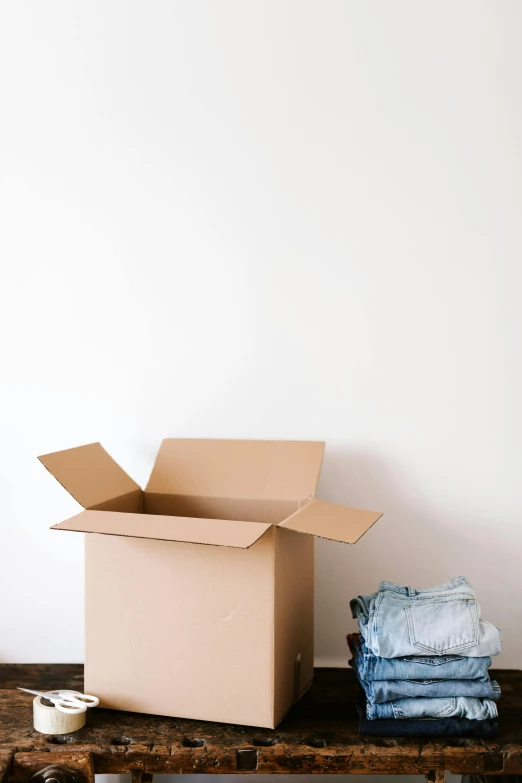 a cardboard box sitting on top of a wooden table, clothes, with a white background, synthetic materials, leaving a room