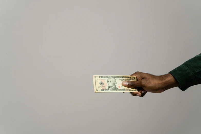 a man holding a stack of money in his hand, by artist, pexels contest winner, man is with black skin, on a gray background, simplistic, without text