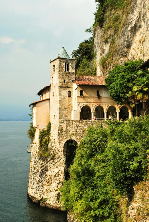 a building sitting on top of a cliff next to the ocean, romanesque, lakeside, italian renaissance, exterior