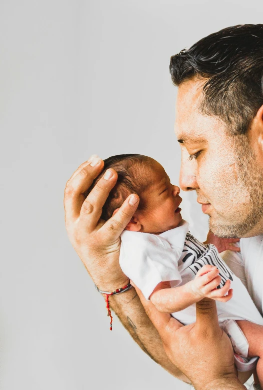 a man holding a baby in his arms, shutterstock contest winner, hand on cheek, portrait of danny gonzalez, profile image, fatherly