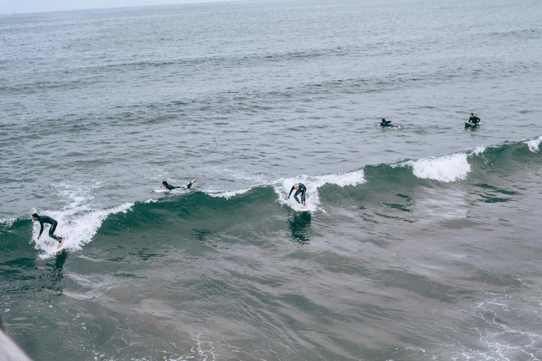 a group of surfers riding a wave in the ocean, a photo, pexels contest winner, grey, thumbnail, low quality footage, bay area