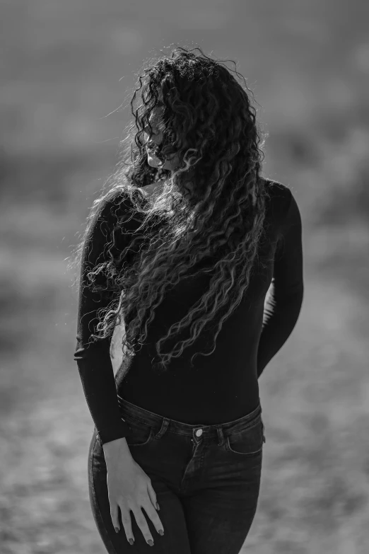 a woman standing in the middle of a dirt road, a black and white photo, inspired by irakli nadar, renaissance, with long curly hair, dreadlock breed hair, ((portrait)), back - lit