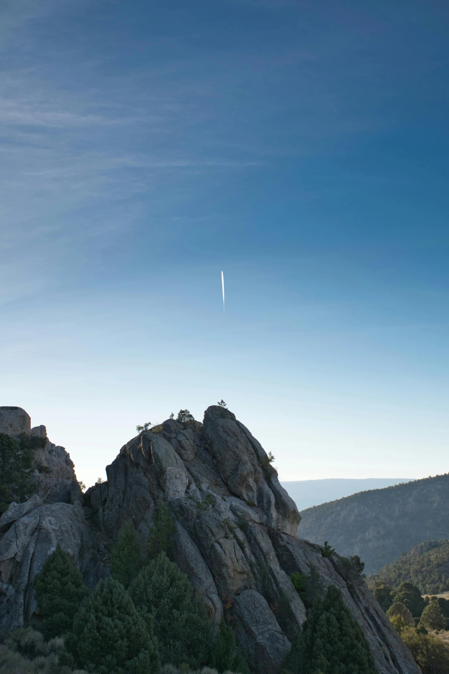 a group of people standing on top of a mountain, rocket launch, yosemite, rocks flying, from afar