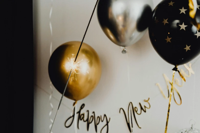 a couple of balloons sitting on top of a table, trending on pexels, gold and black, new years eve, thumbnail, amanda lilleston