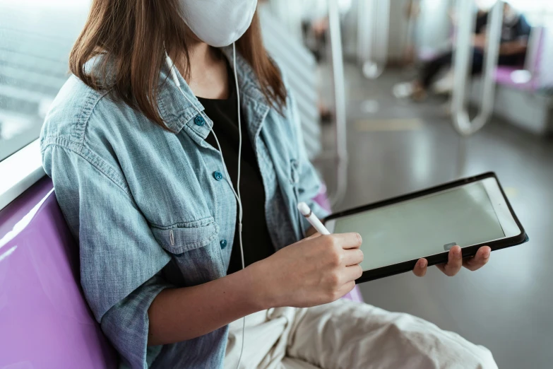 a woman sitting on a train holding a tablet computer, a picture, trending on pexels, graffiti, people are wearing masks, from reading to playing games, worksafe. instagram photo, profile image