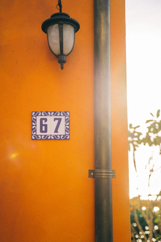 a street sign mounted to the side of a building, unsplash, azulejo, orange and purple color scheme, r-number, at home