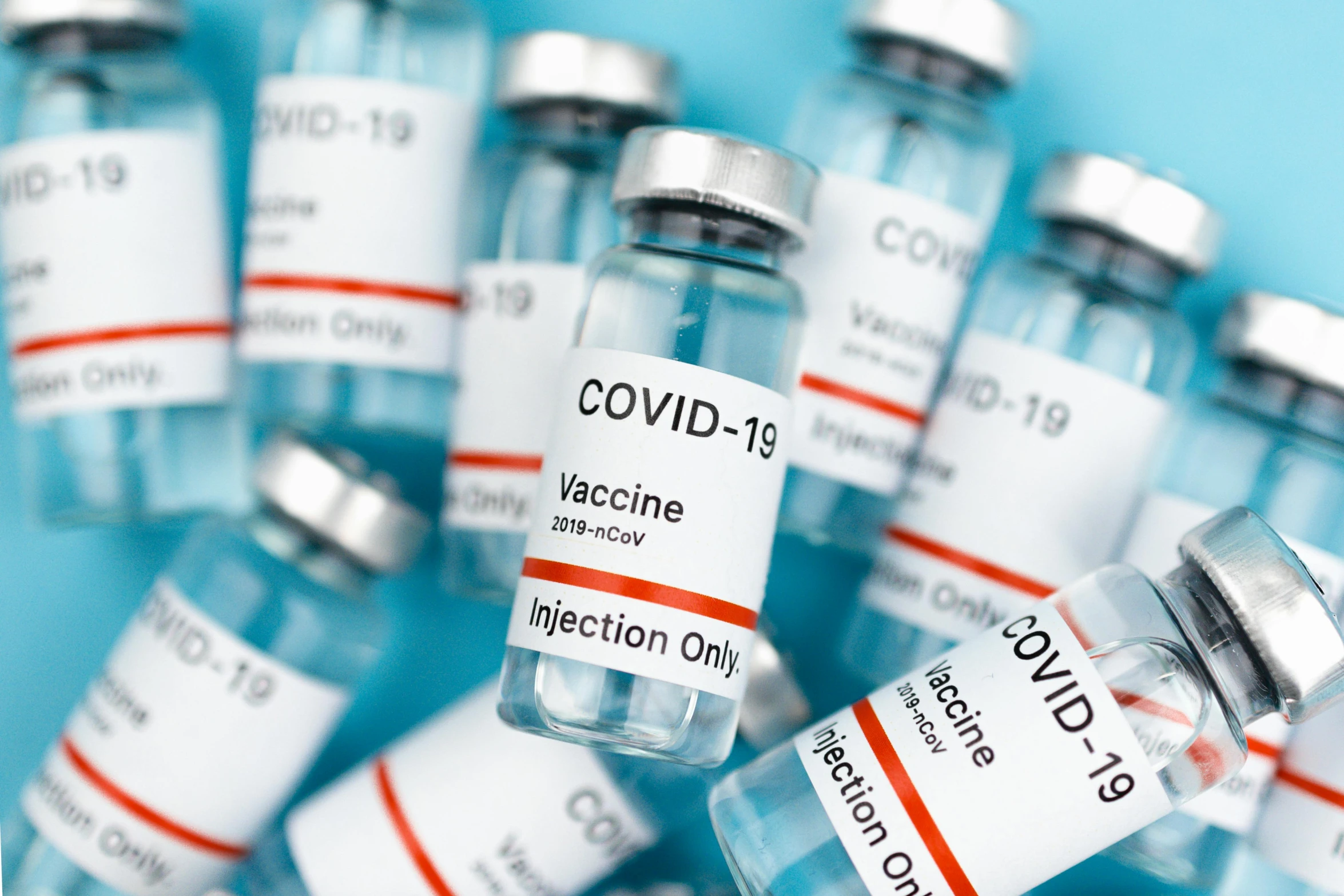 a group of vials filled with vaccines on a blue surface, instagram post, covid, a labeled, gray