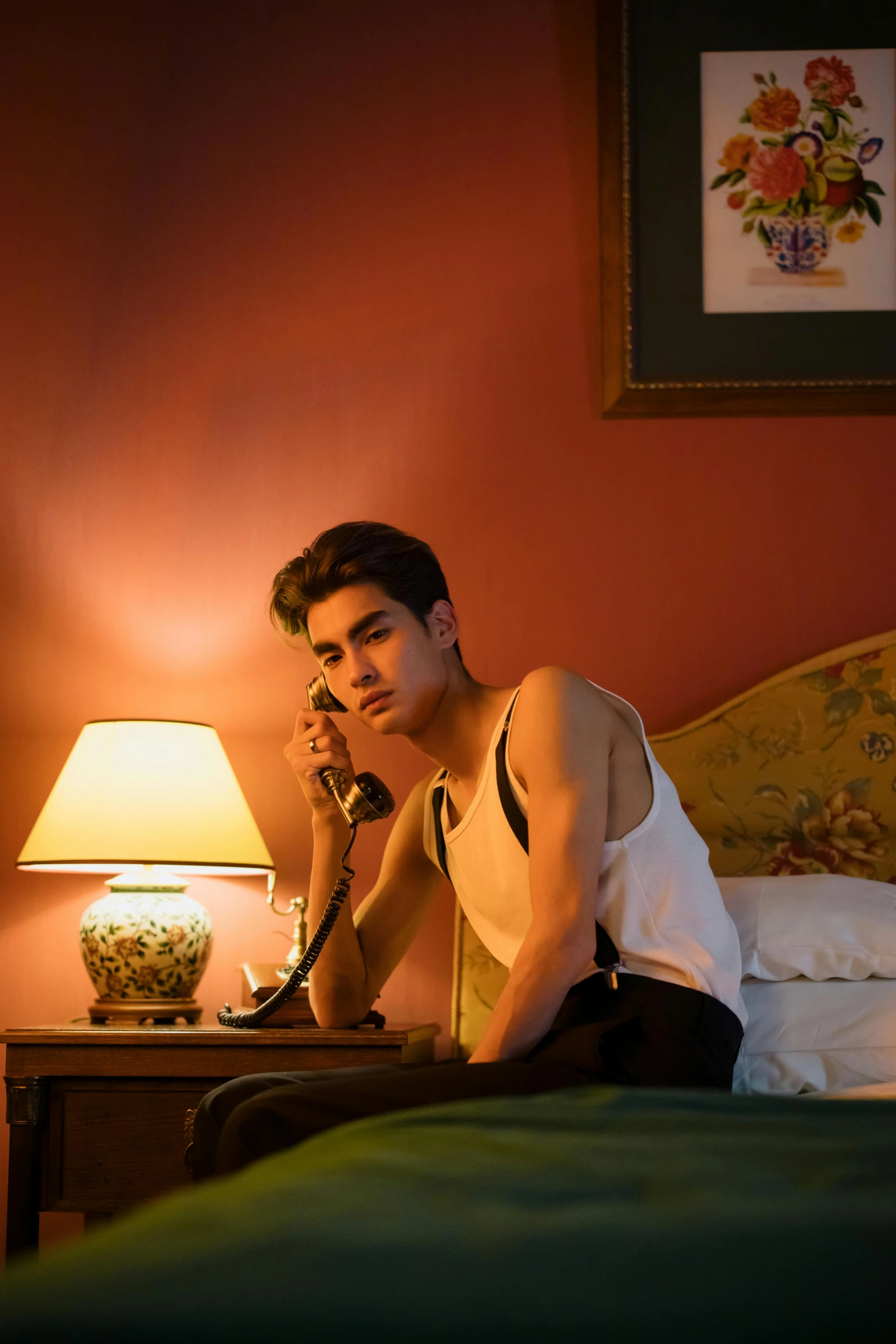 a man sitting on a bed talking on a phone, inspired by Nan Goldin, trending on pexels, magic realism, joe keery, beautiful androgynous prince, asian male, paris hotel style