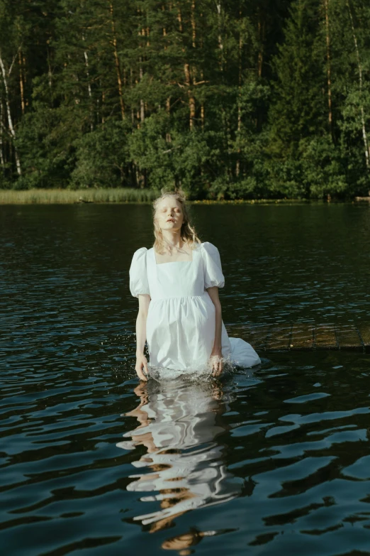 a woman in a white dress standing in a body of water, an album cover, by Anna Boch, unsplash, renaissance, blonde swedish woman, greta thunberg, ignant, still pond