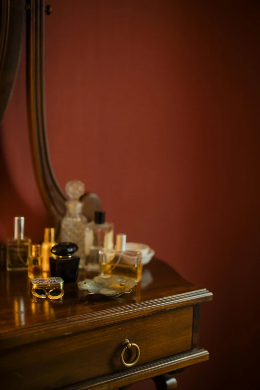 a table topped with bottles of perfume next to a mirror, inspired by Allan Ramsay, pexels, renaissance, red room, brown, ochre, detail shot