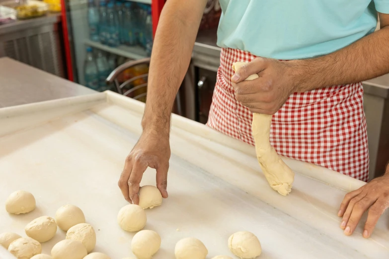 a man standing in front of a tray of doughnuts, trending on pexels, chopping hands, holding a baguette, wet clay, holding a thick staff