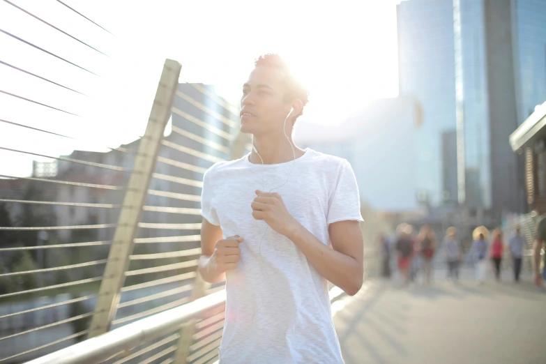 a man in a white shirt standing on a bridge, pexels contest winner, happening, wearing fitness gear, sunlight filtering through skin, music being played, people running
