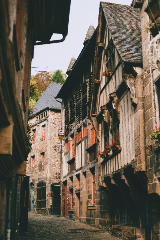 a narrow cobblestone street lined with old buildings, inspired by Gaston Bussière, pexels contest winner, renaissance, rennes - le - chateau, houses on stilts, brown, gif