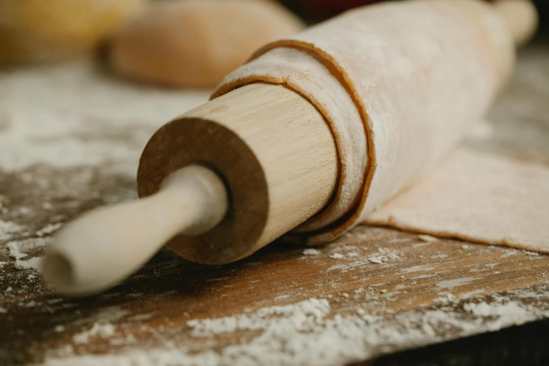 a rolling pin sitting on top of a wooden table, inspired by Sarah Lucas, trending on pexels, flour dust, holding a wooden staff, piping, bespoke