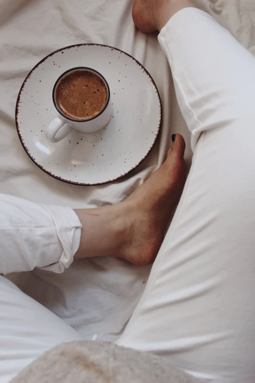 a person laying in bed with a cup of coffee, by Lucia Peka, barefeet, cold brew coffee ), milk and mocha style, very comfy]