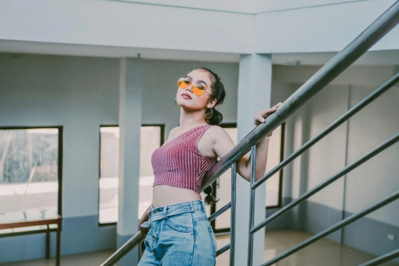 a woman standing at the top of a set of stairs, a picture, inspired by Elsa Bleda, trending on pexels, aestheticism, girl wearing round glasses, croptop, standing in corner of room, cindy avelino
