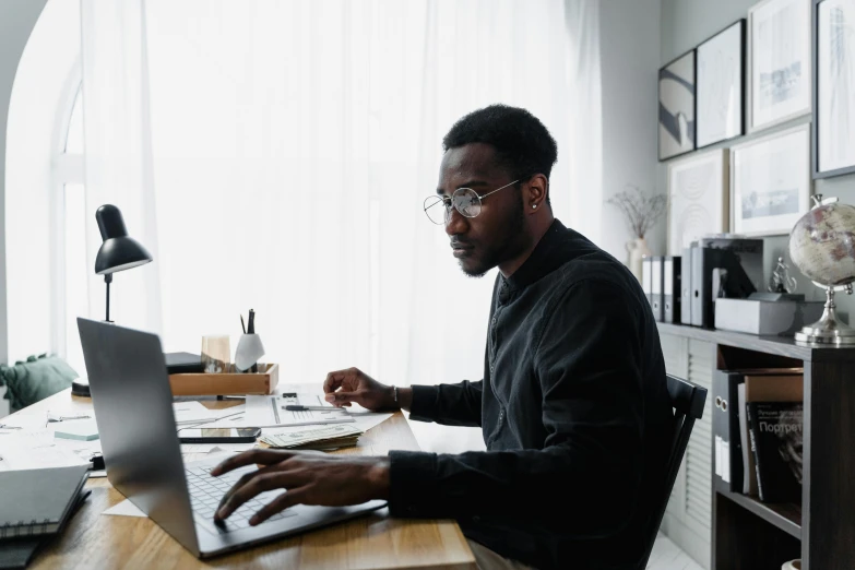 a man sitting at a desk using a laptop computer, trending on pexels, black people, trending on attestation, wearing black rimmed glasses, thumbnail