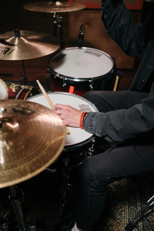 a man sitting in front of a drum set, corrected hand, neck zoomed in, a high angle shot, temples