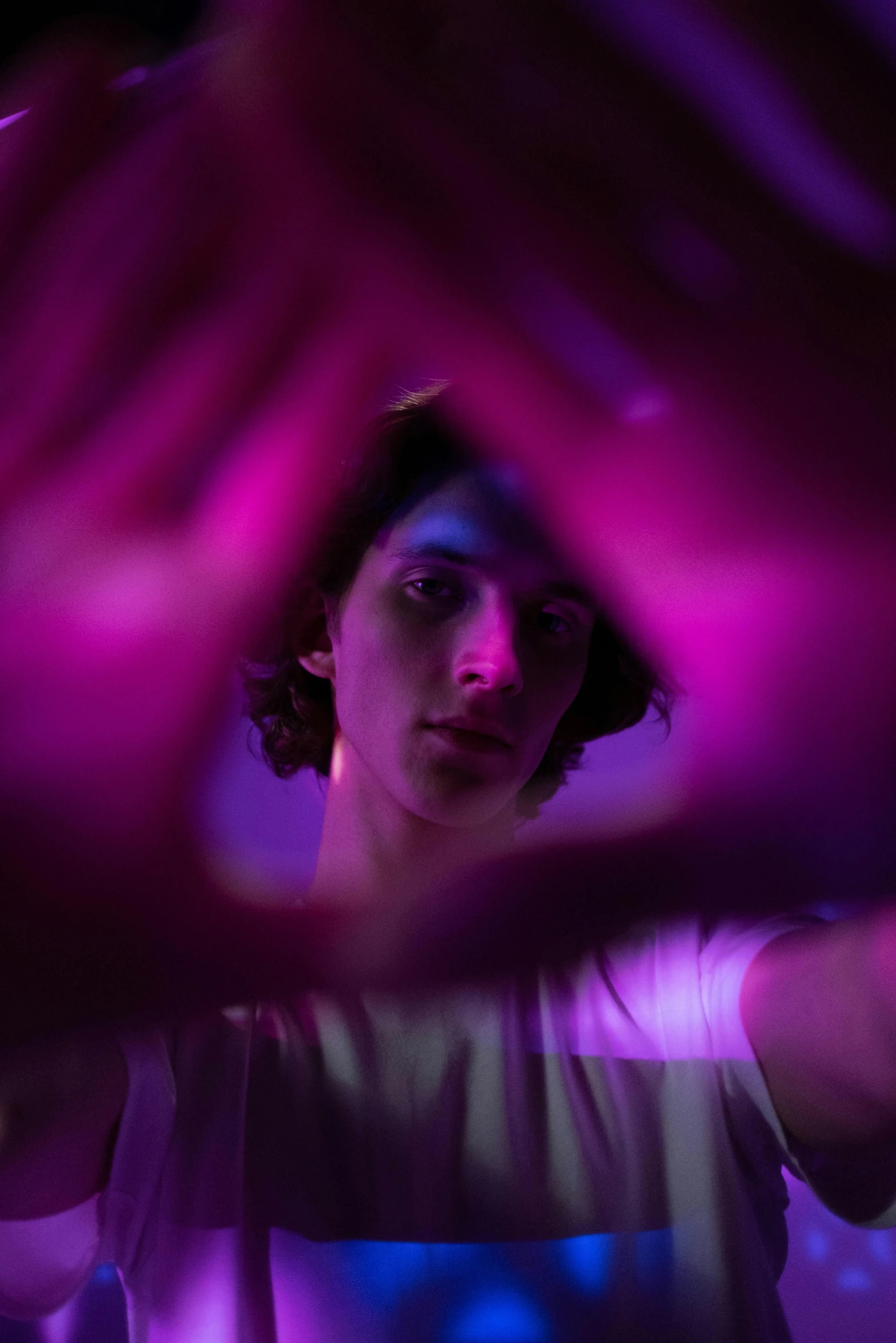 a person making a heart shape with their hands, pexels contest winner, holography, portrait of timothee chalamet, bright pink purple lights, medium portrait top light, serious lighting