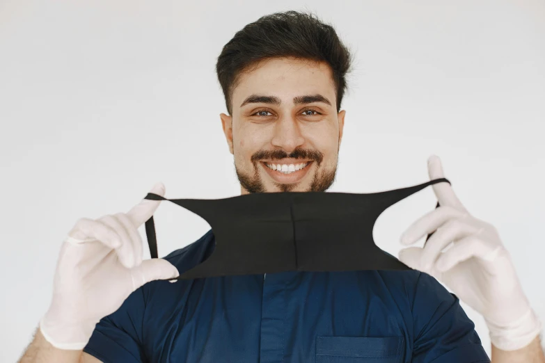 a man in a blue shirt and white gloves holding a black piece of paper, pexels contest winner, plasticien, dentist, open v chest clothes, avatar image, neoprene