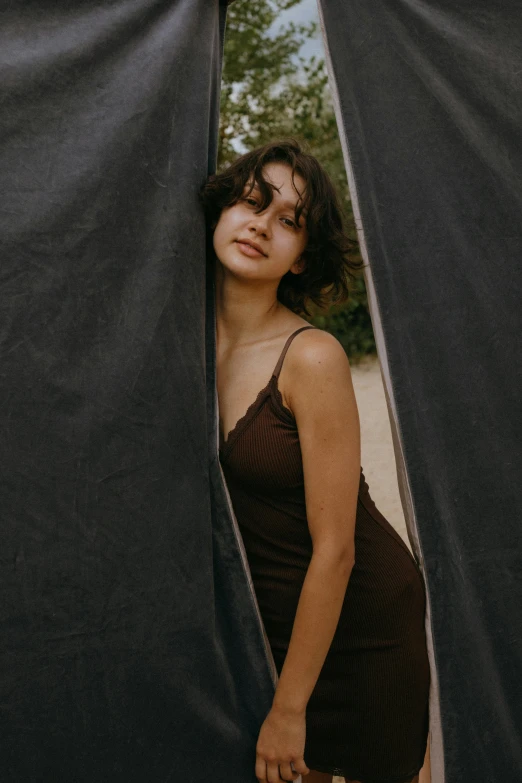 a woman standing in front of a black curtain, camping, dark brown hair and tan skin, asher duran, high quality photo